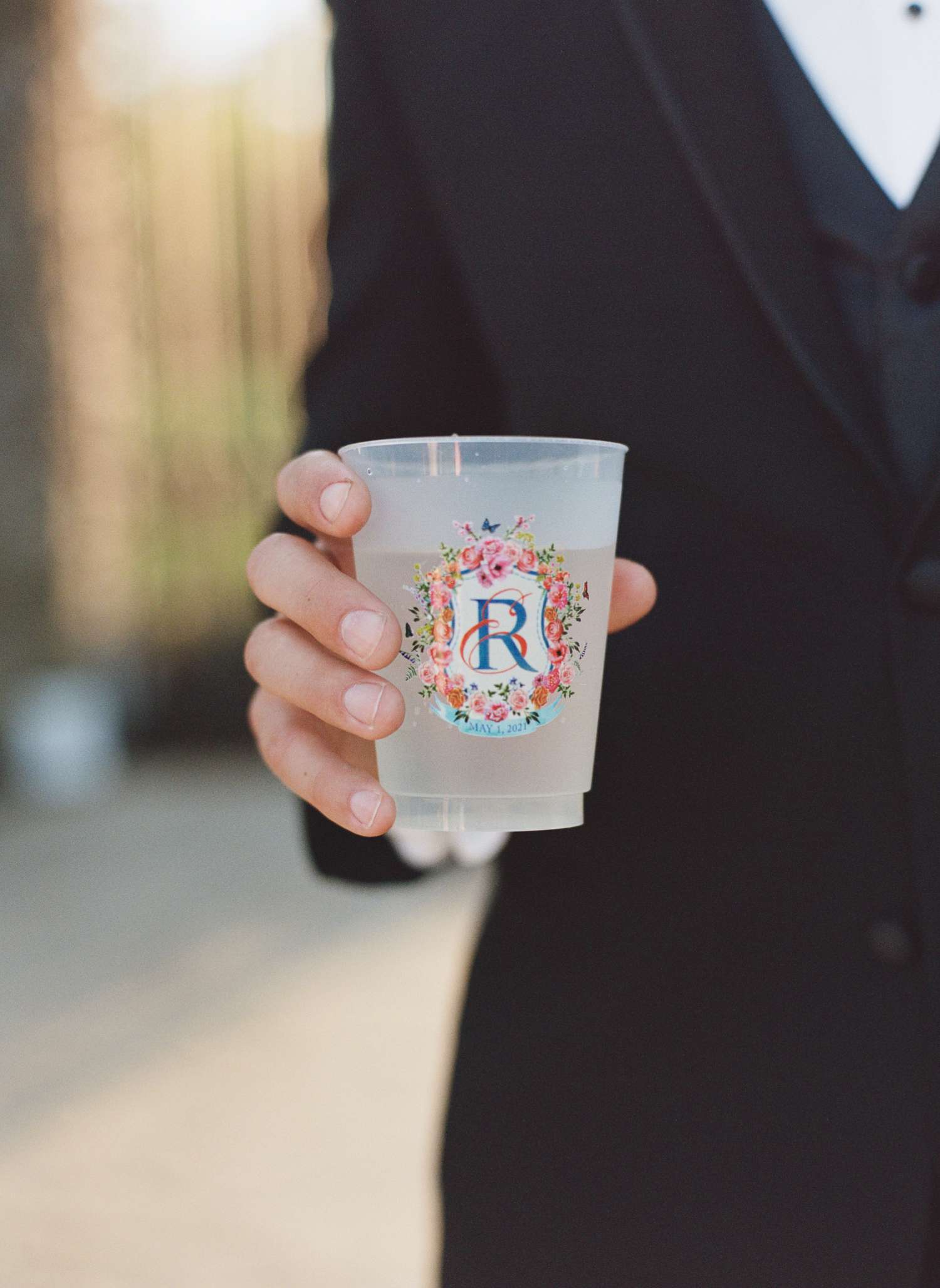Groom Holding Clear Plastic Cup with Custom Wedding Crest