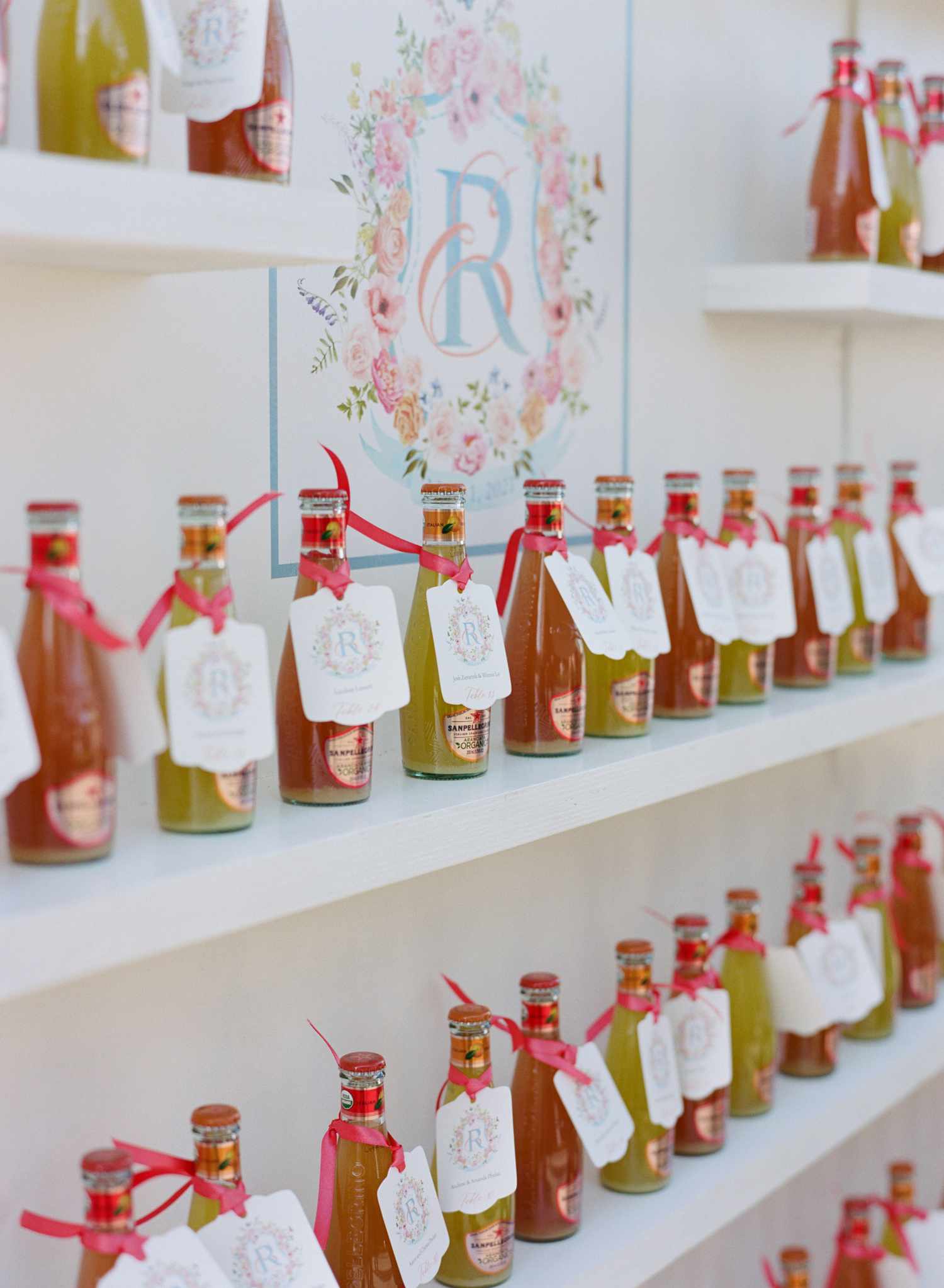 Mini Alcohol Bottle Wedding Favors on Wall with Tags Featuring Couples' Custom Wedding Crest