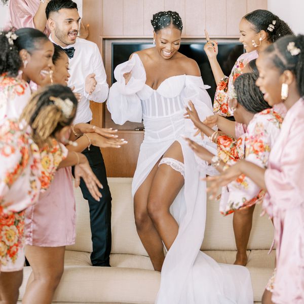 Bride dancing with her bridal party in a white dress while wearing a wedding garter