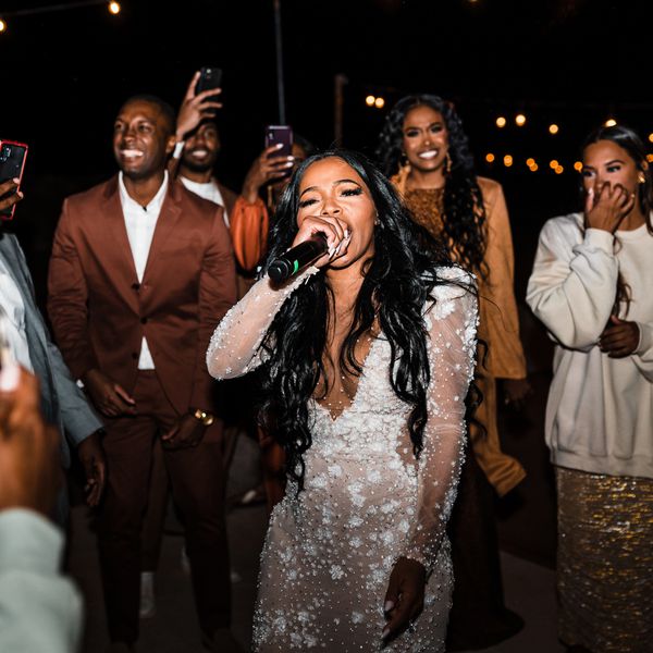 bride singing into a microphone surrounded by her wedding guests