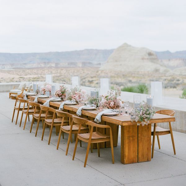 Wooden banquet table with pink flower table arrangements and matching wooden chairs