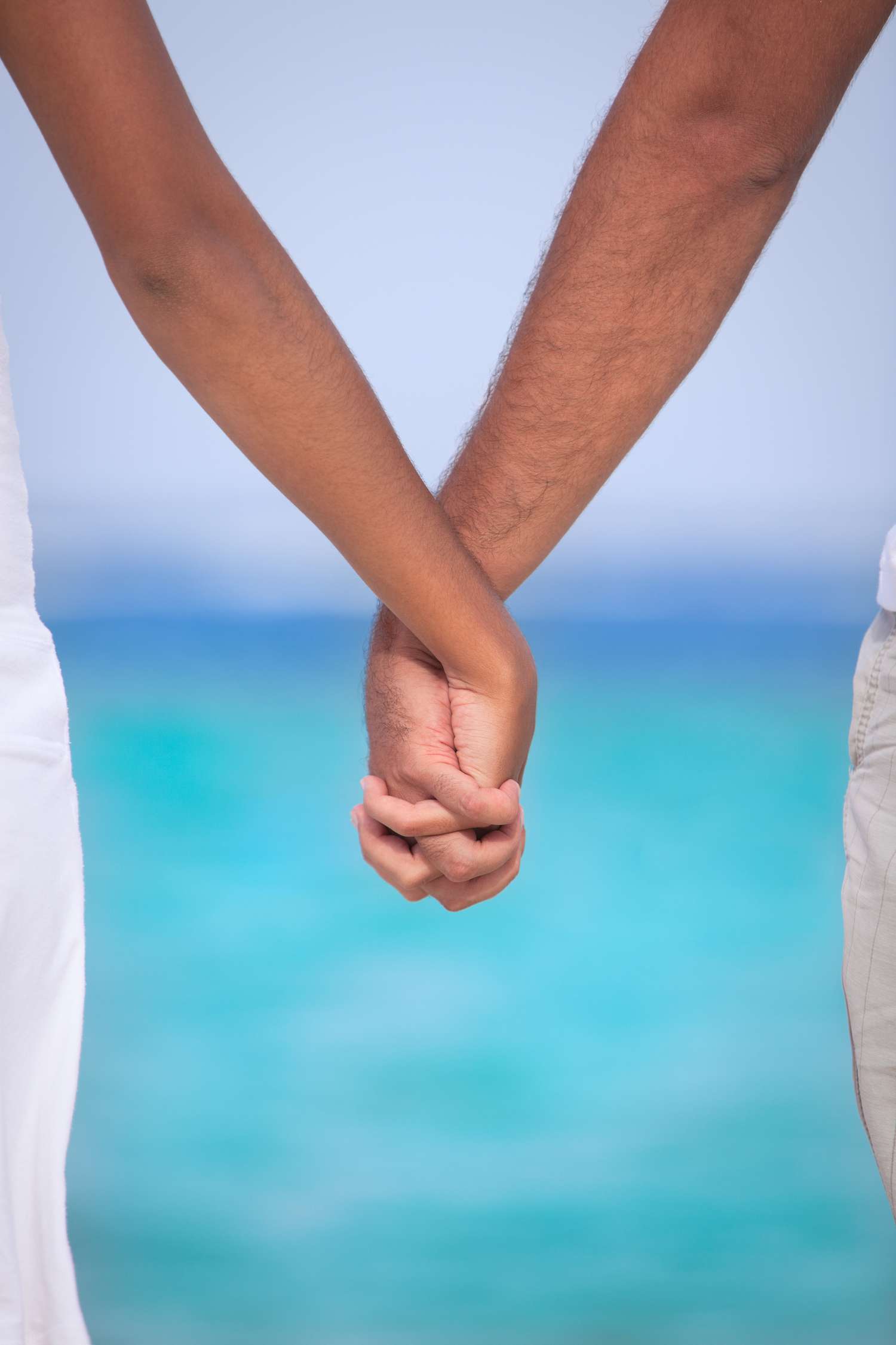 Closeup of Bride and Groom Holding Hands in Front of Ocean