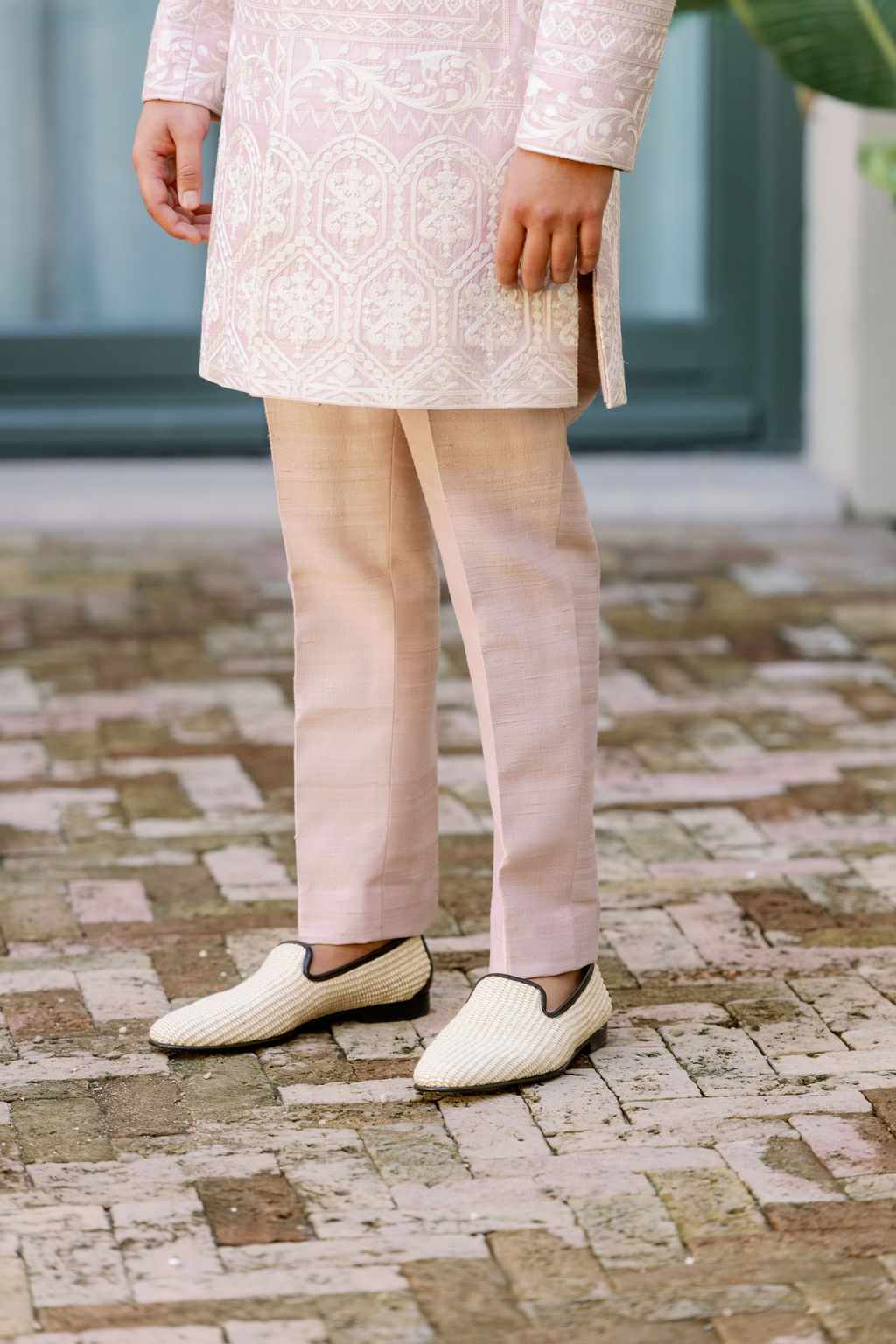 Closeup of Groom's Pink Embroidered Kurta and Pants With White Shoes Lined With Black