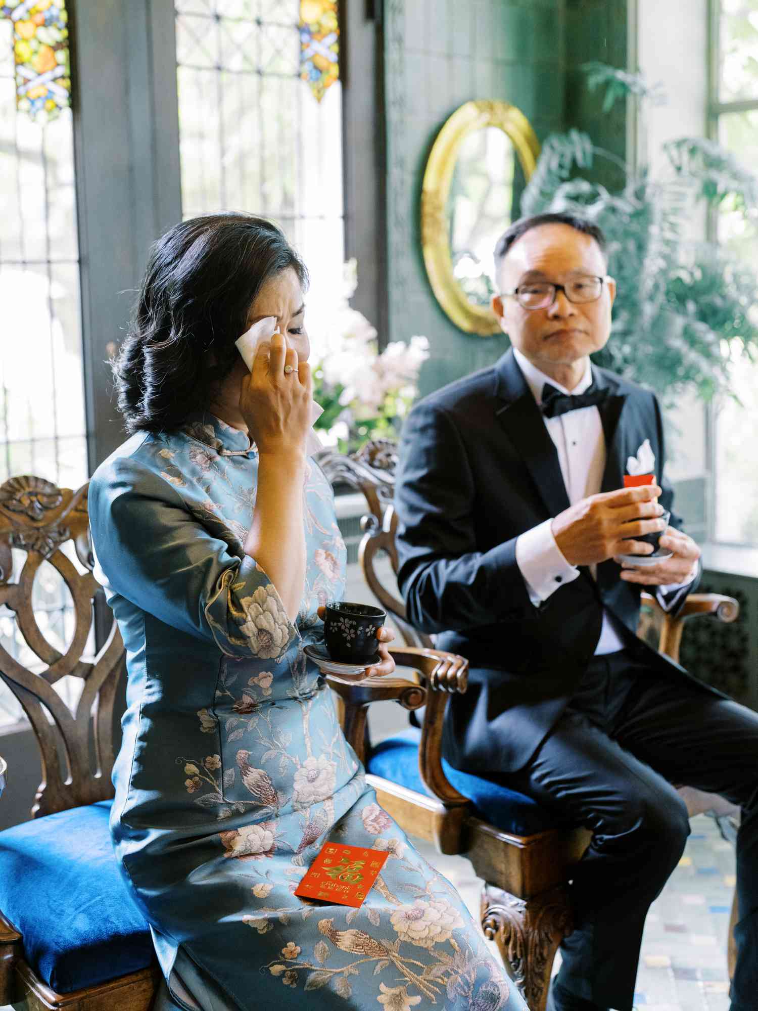 Mother of the Bride Dabbing Tears While Sitting Next to Husband
