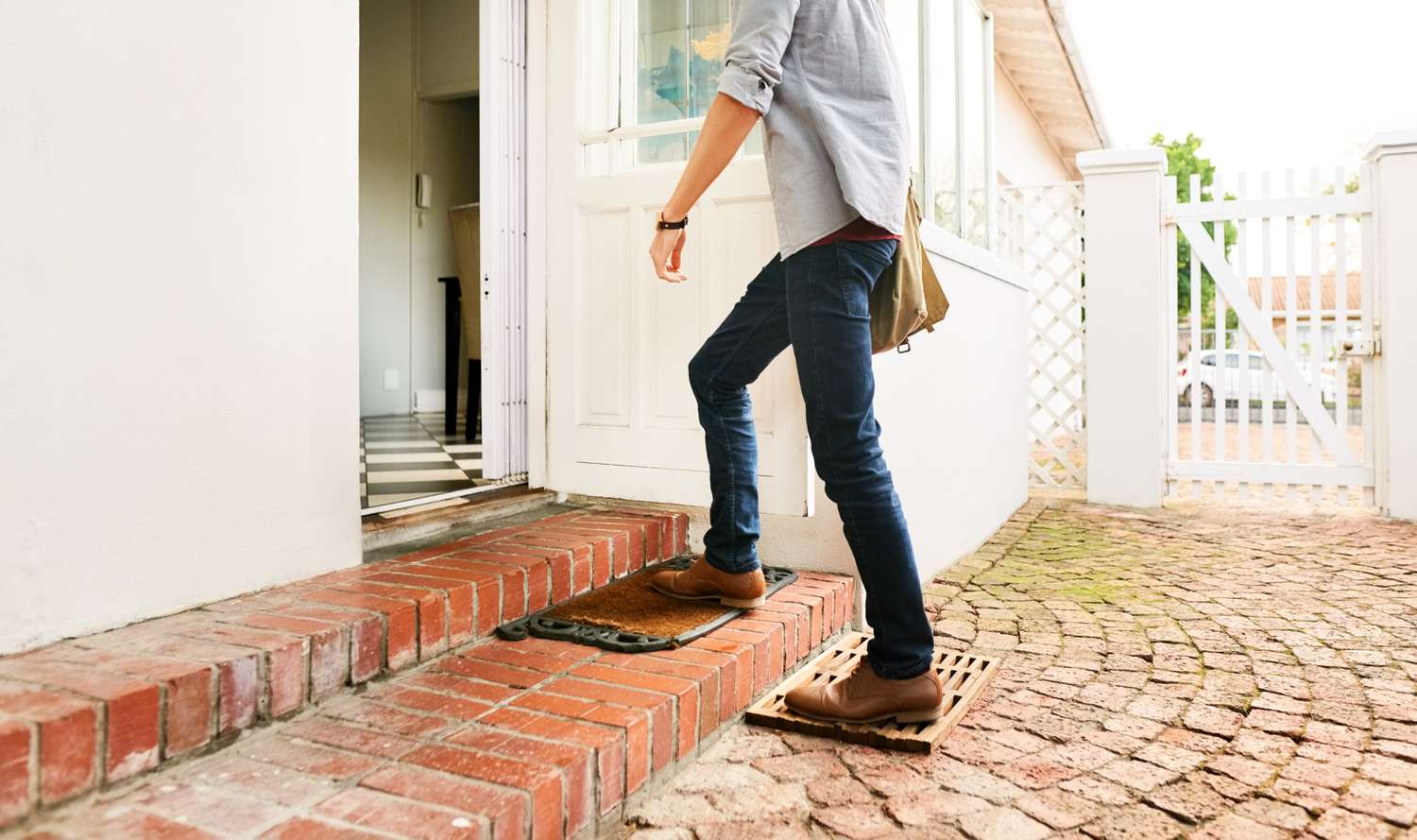 Lower Half of Man in Jeans Walking Up Brick Steps to Front Door of Home