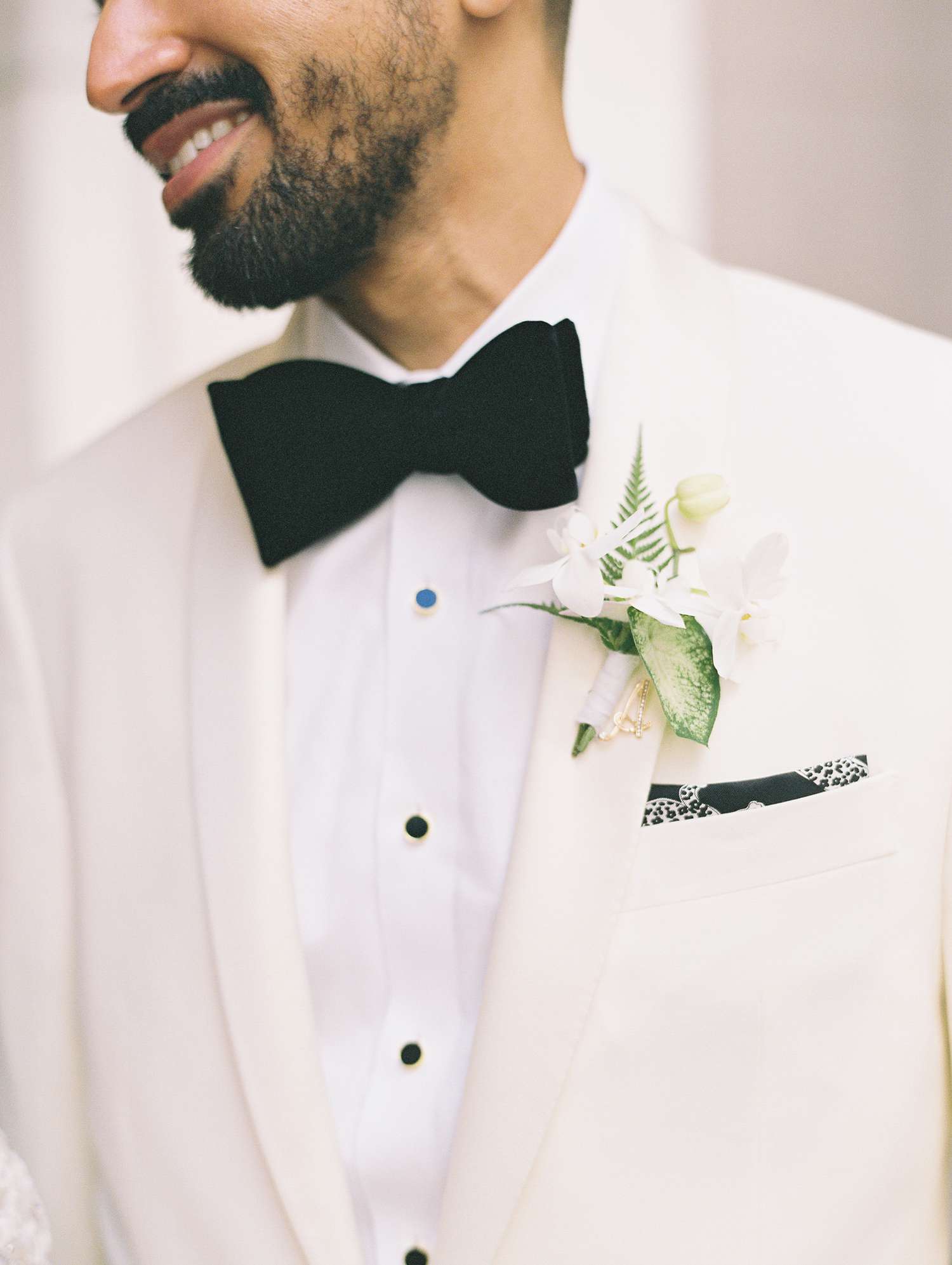 Closeup of Black Bow Tie, White Floral Boutonniere, and Printed Pocket Square
