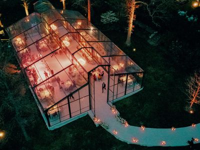 Aerial View of Clear-Top Wedding Tent with Glowing Candles and Mingling Guests