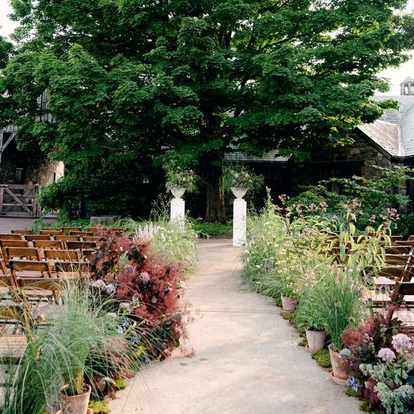 Outdoor Wedding Ceremony Venue With Potted Flowers and Greenery Lining the Aisle