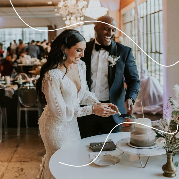 laughing bride and groom cutting two-tiered wedding cake