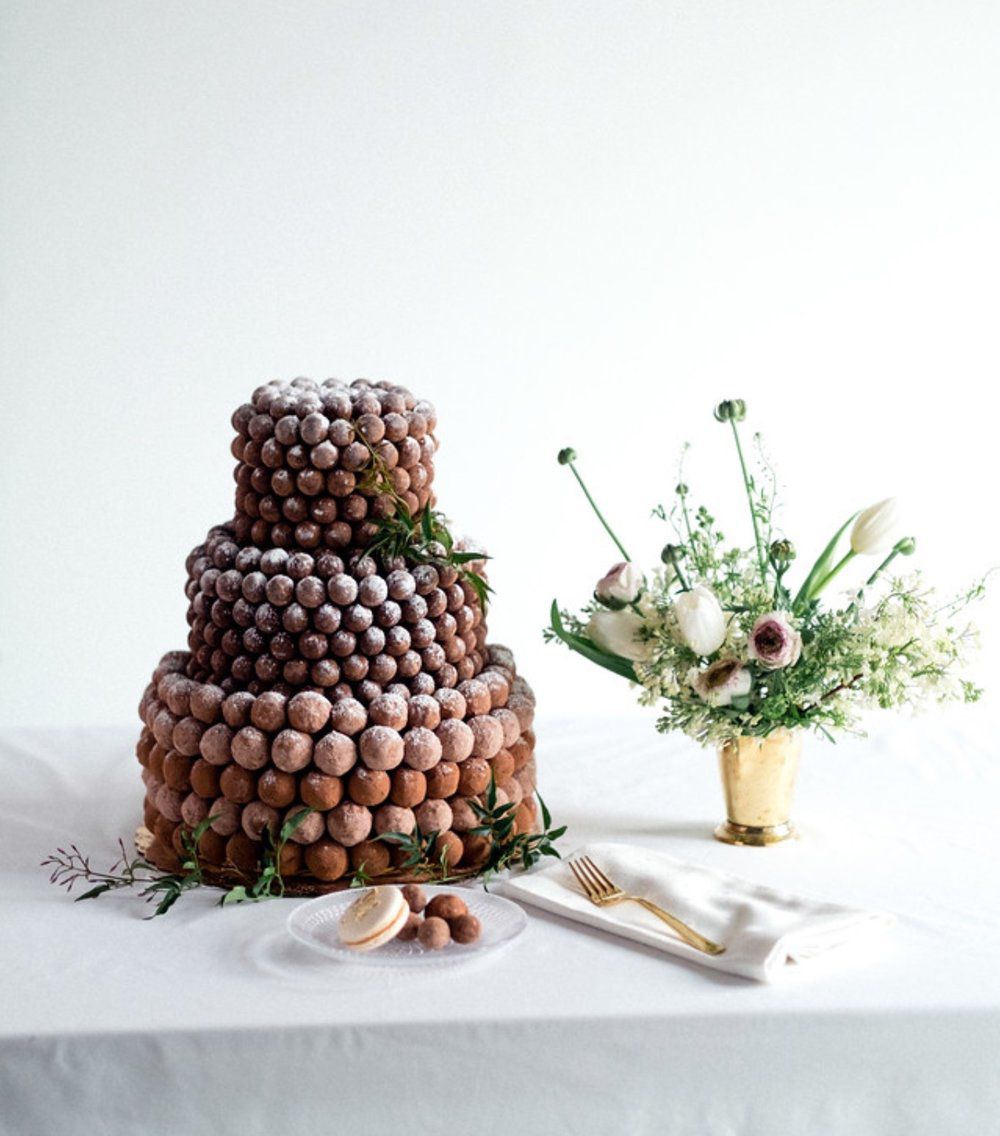 Three-tier cake with truffles next to a floral arrangement