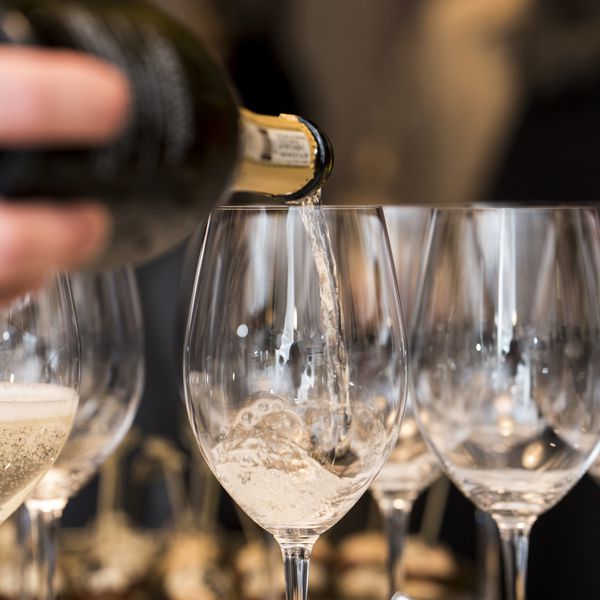Close up photo of someone pouring a champagne into a glasses.