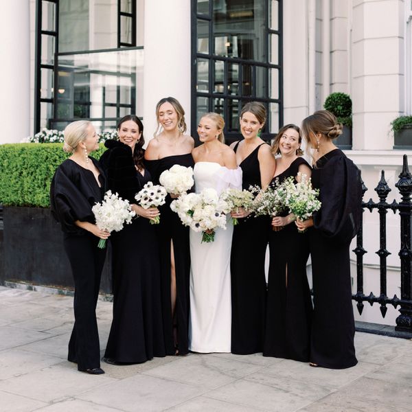 bride posing with her bridal party who are all wearing black bridesmaid dresses