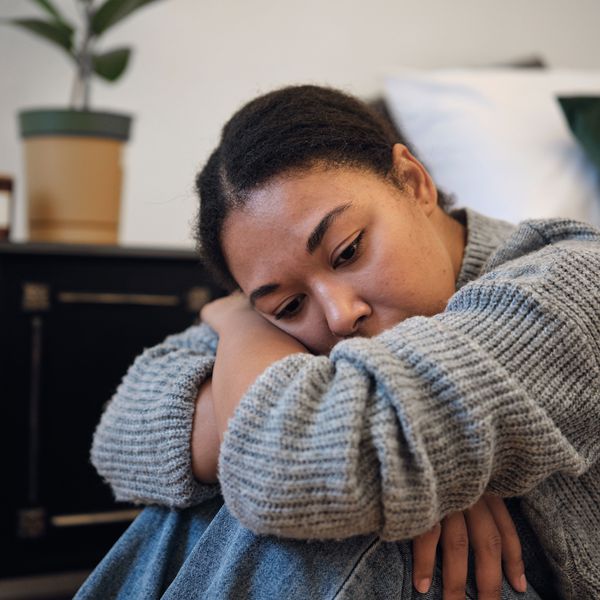 Woman Rests Her Head In Her Lap, Sad From Experiencing Verbal Cruelty