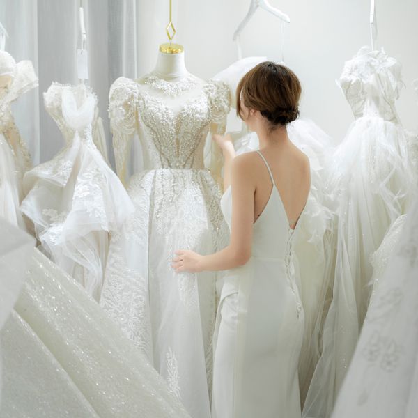 Woman Browsing Rack of Wedding Dresses in a Salon