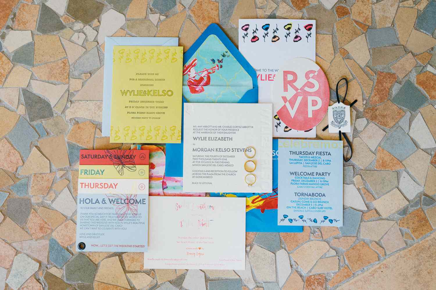 Colorful blue, yellow, red, and white wedding invitation invitation suite with programming inserts, butterfly, floral and mariachi illustrations, and an oval rsvp card