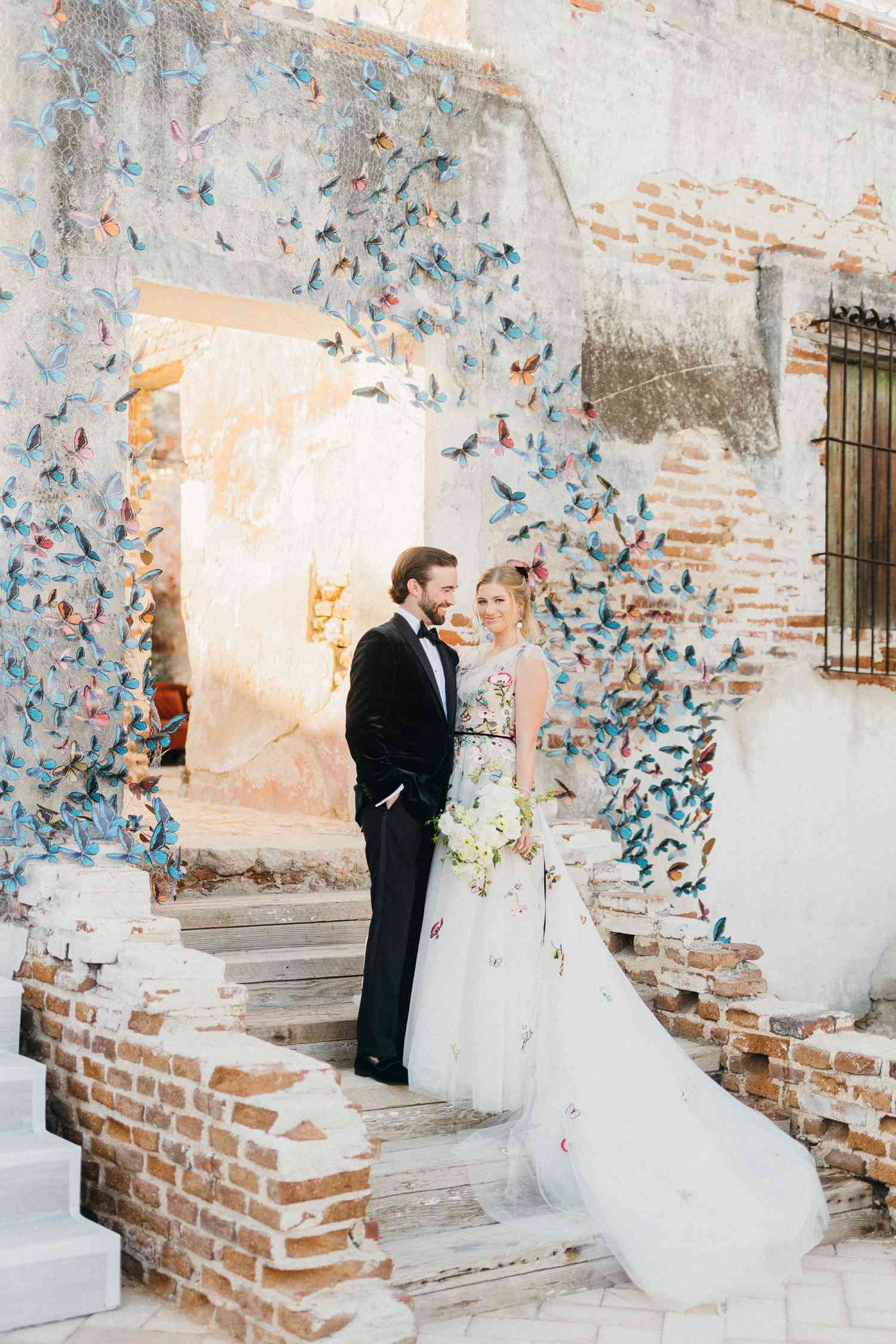 Bride and groom posing in front of arched entrance of colorful butterflies