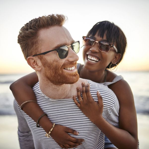 Young Couple Hugging on the Beach at Sunset Wearing Sunglasses