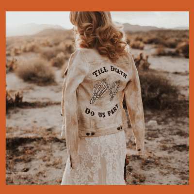 bride wearing "til death do us part" skeleton jean jacket and wedding dress in the desert