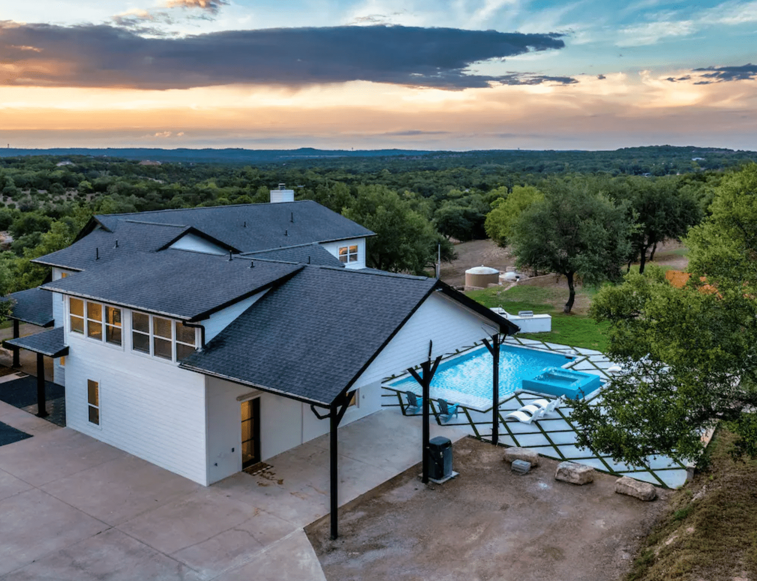 Whitewashed home with outdoor pool surrounded by nature at sunset
