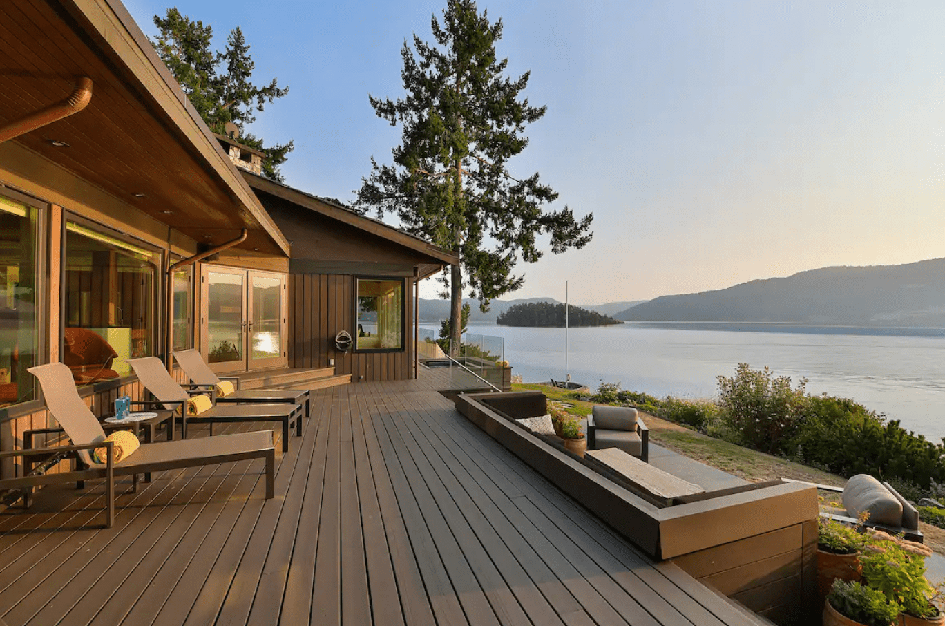 Home With Wooden Deck and Lounge Furniture Overlooking Mountains and Lake