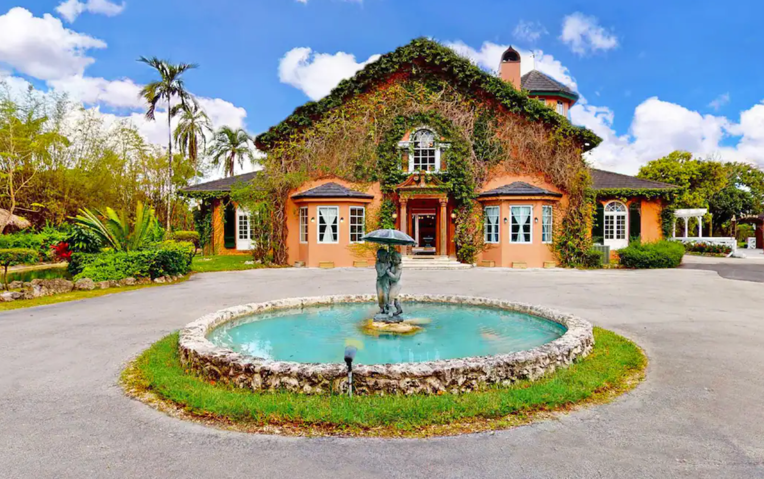 Greenery-covered estate with fountain in front of it