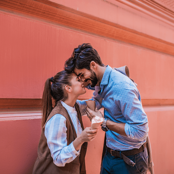 young couple touching foreheads while holding ice cream cones