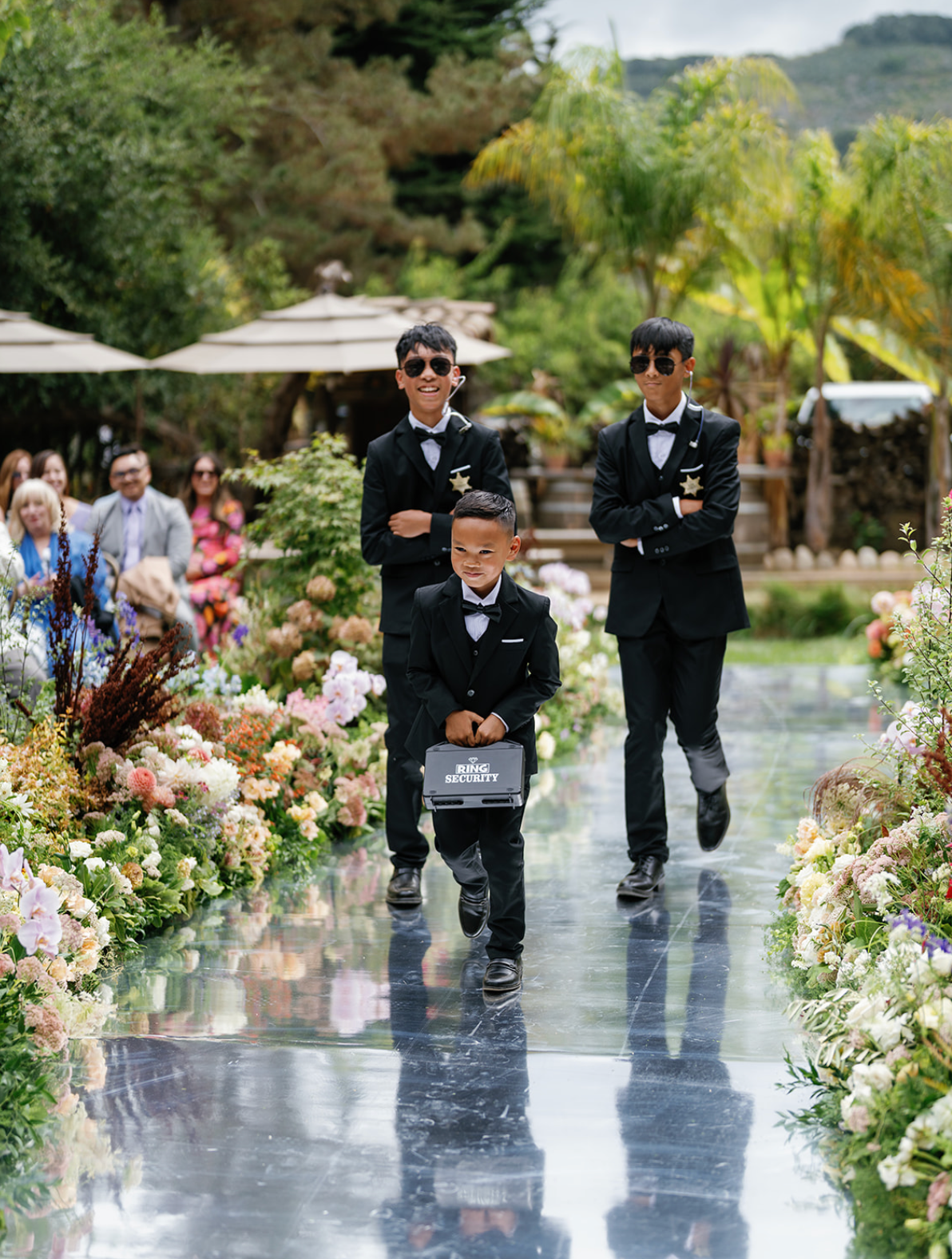 Ring bearers dressed like security guards, with the younger one holding a lockbox
