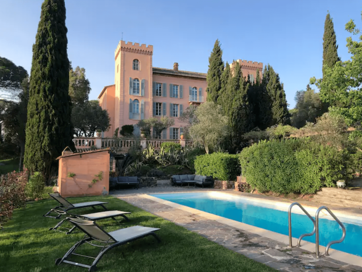 Pool With Stone Deck, Lounge Chairs on Grass, and Castle in Background