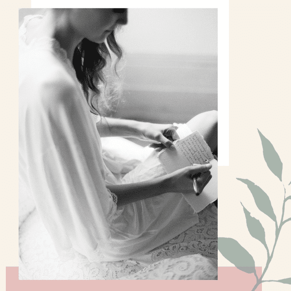 Black and white photo of a woman writing her vows on a card over an illustration.
